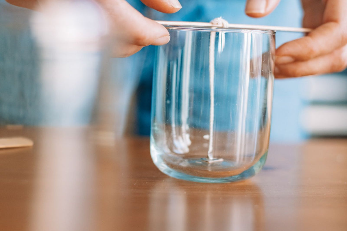 Centrage de la mèche en coton dans le contenant en verre d'une future bougie