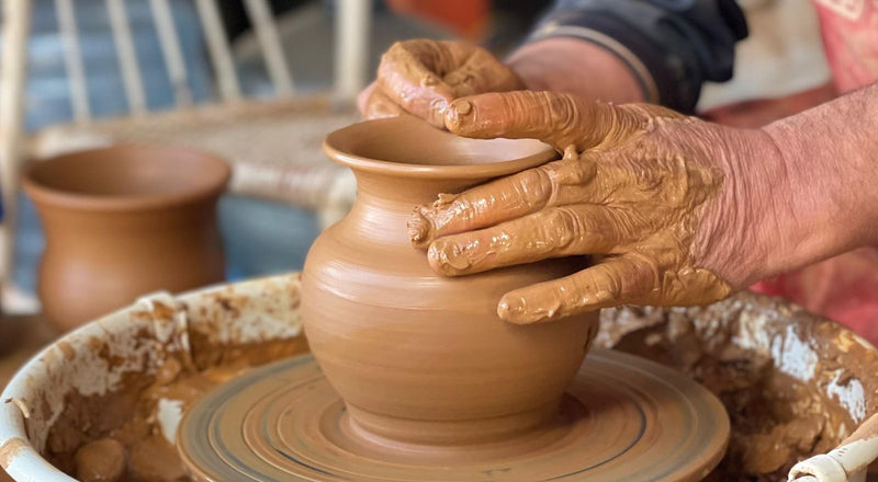 Mains façonnant un pot en argile sur le tour de potière