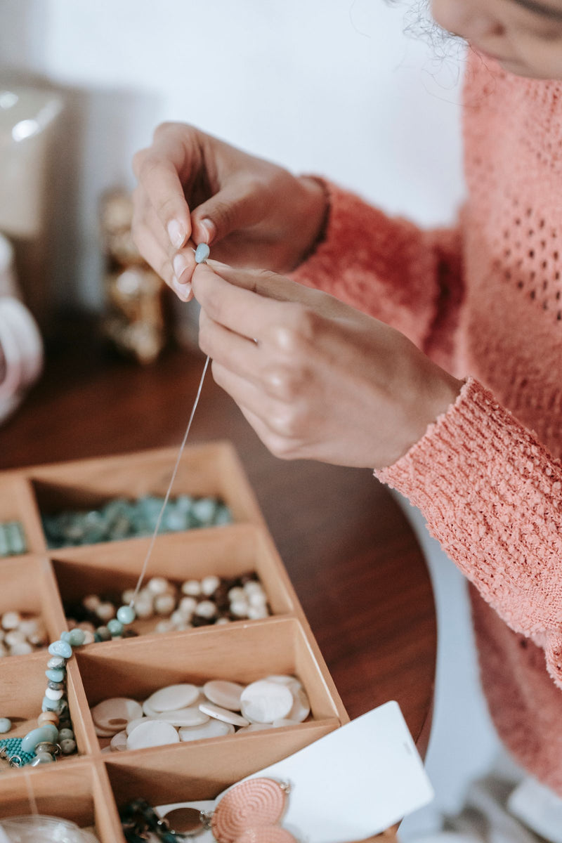 Mains enfilant des perles pour un bijou fait main
