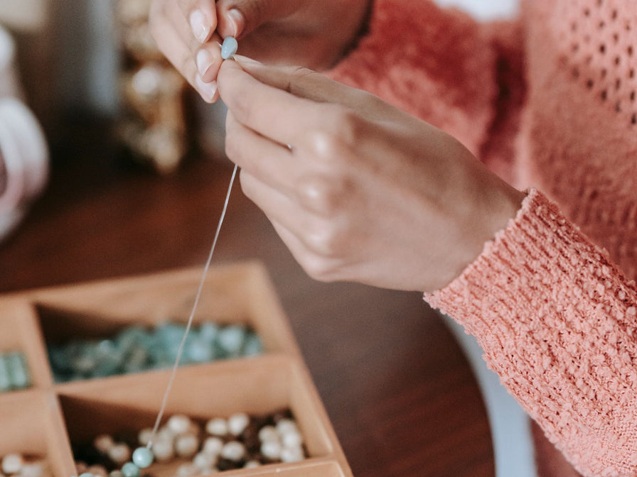 Mains enfilant des perles pour un bijou fait main