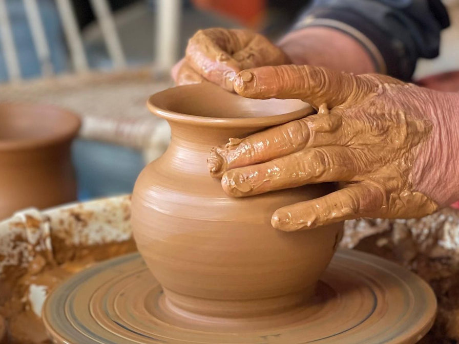 Mains façonnant un pot en argile sur un tour de potier