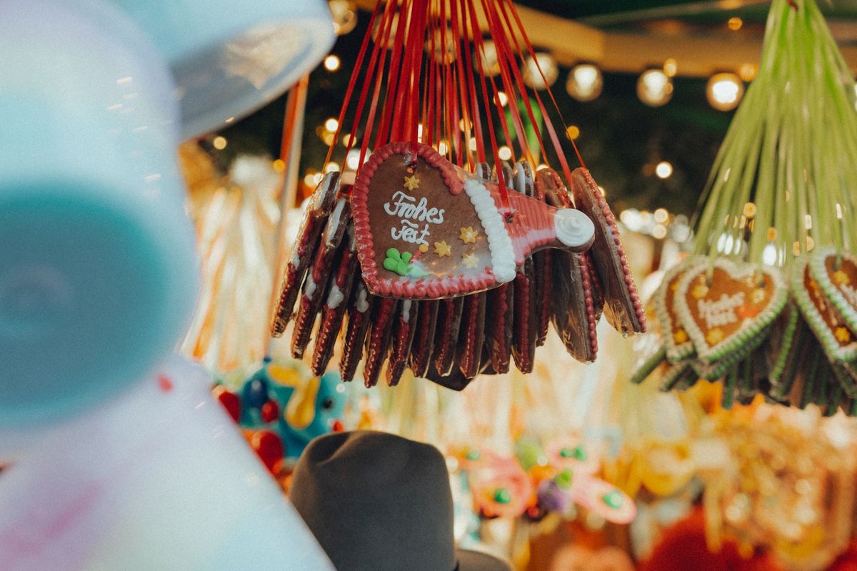 Cœurs en pain d'épices suspendus par des rubans rouges à un stand de marché de Noël illuminé