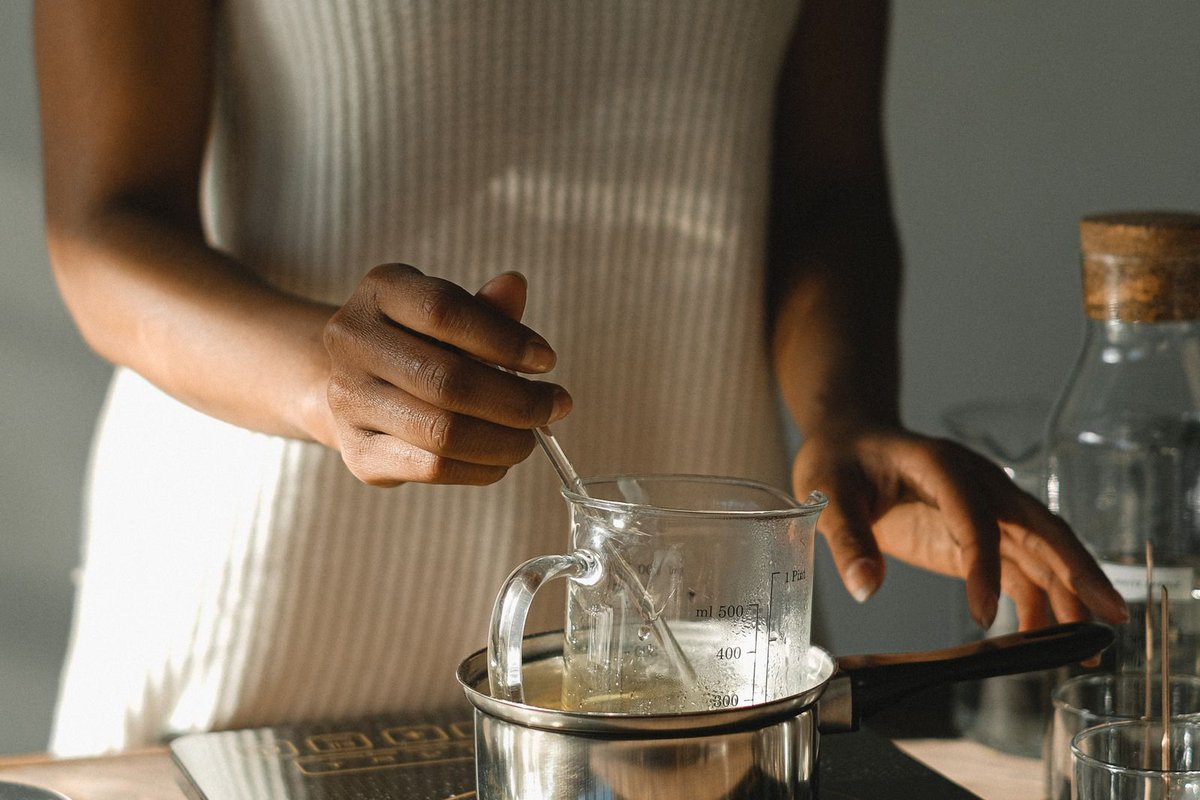 Cire fondue au bain-marie dans la lumière dorée de l'atelier de bougies