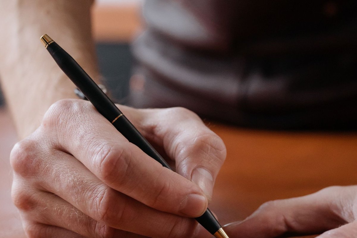 Mains traçant les repères au stylo sur une pièce de cuir avant la découpe
