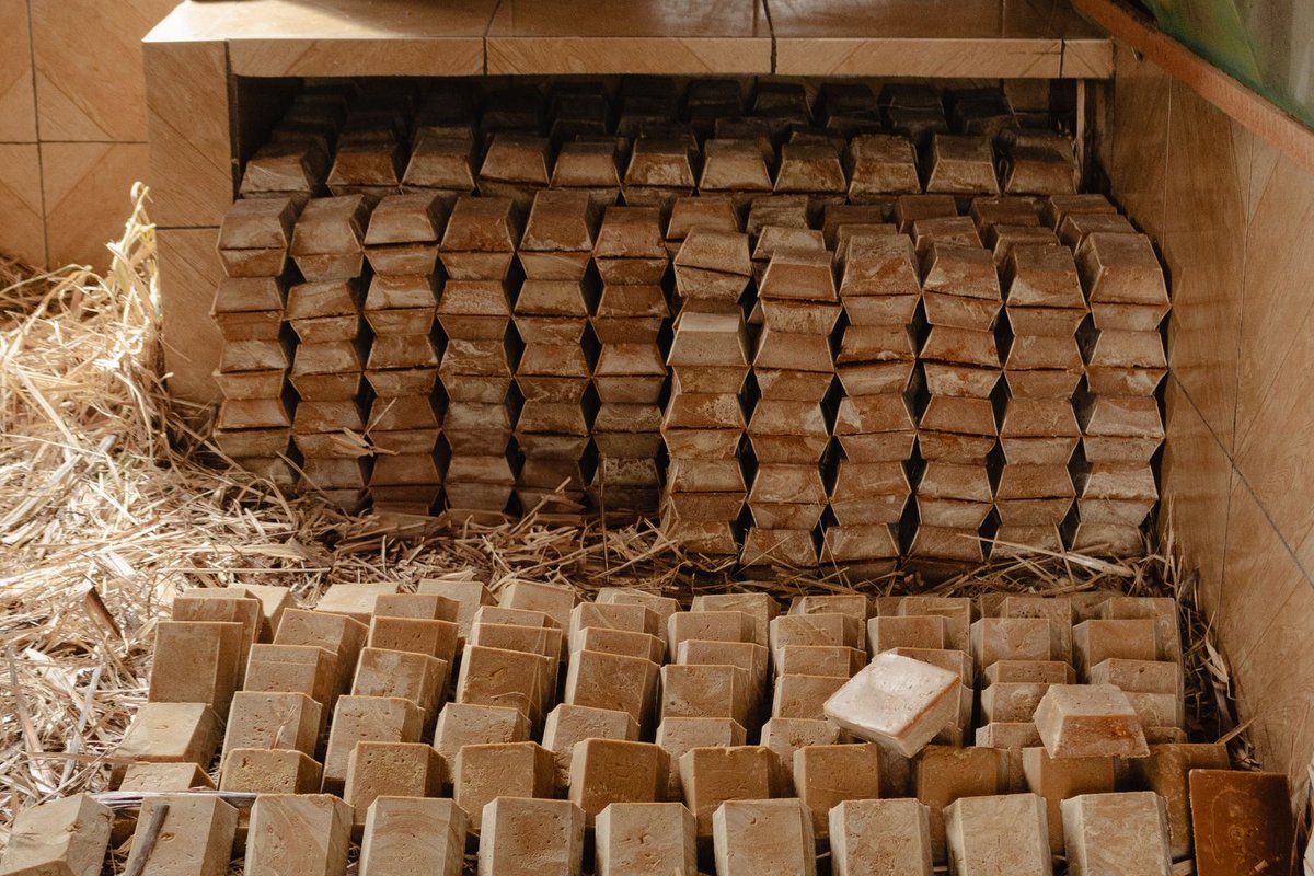 Rangées régulières de savons artisanaux en cure sur la paille d'une savonnerie