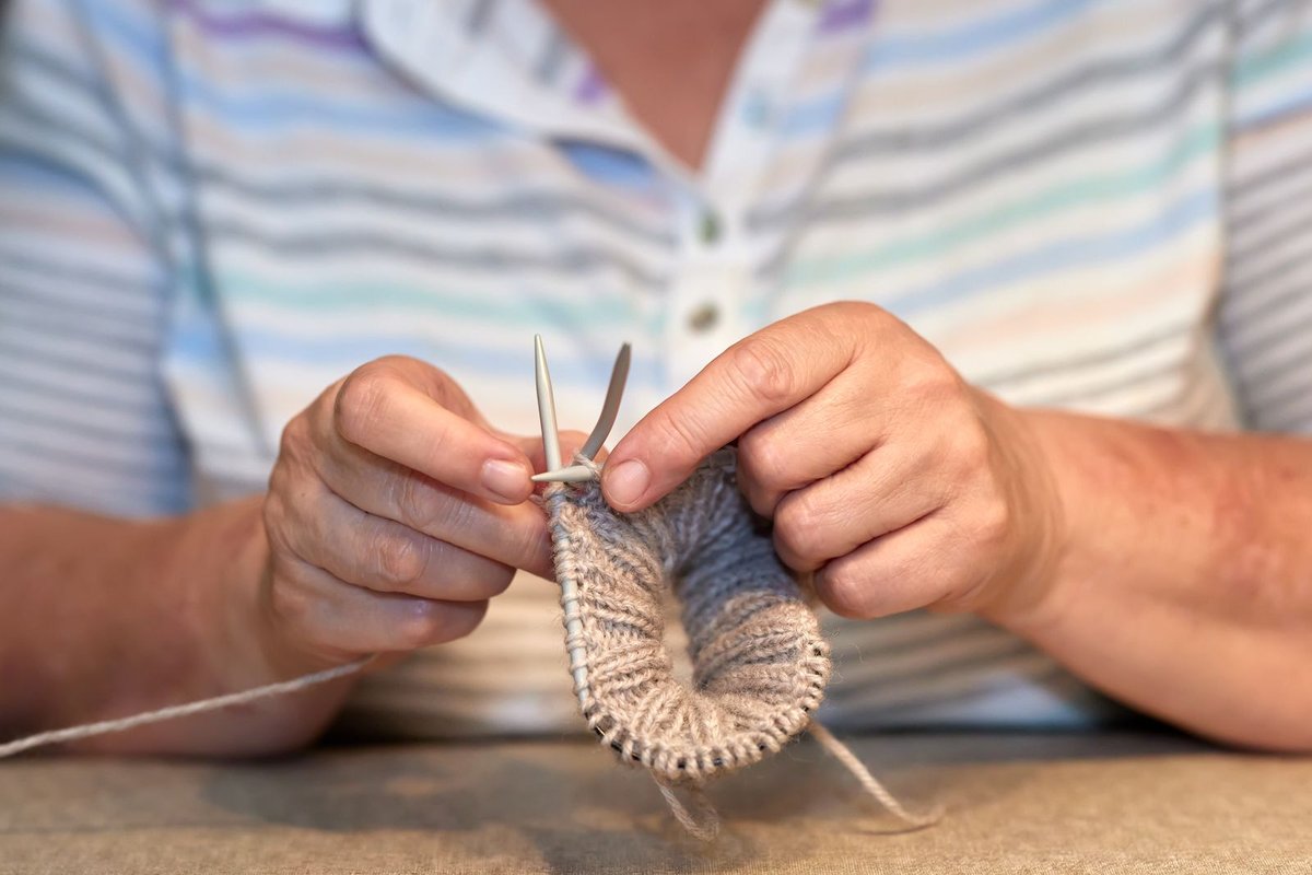 Tricot en rond aux aiguilles, côtes de laine naturelle entre les mains