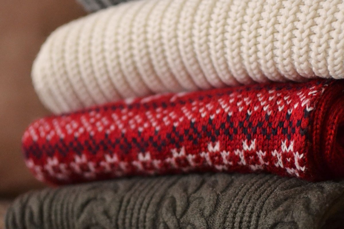 Pile de pulls tricotés main soigneusement pliés, prêts à être mis en vente