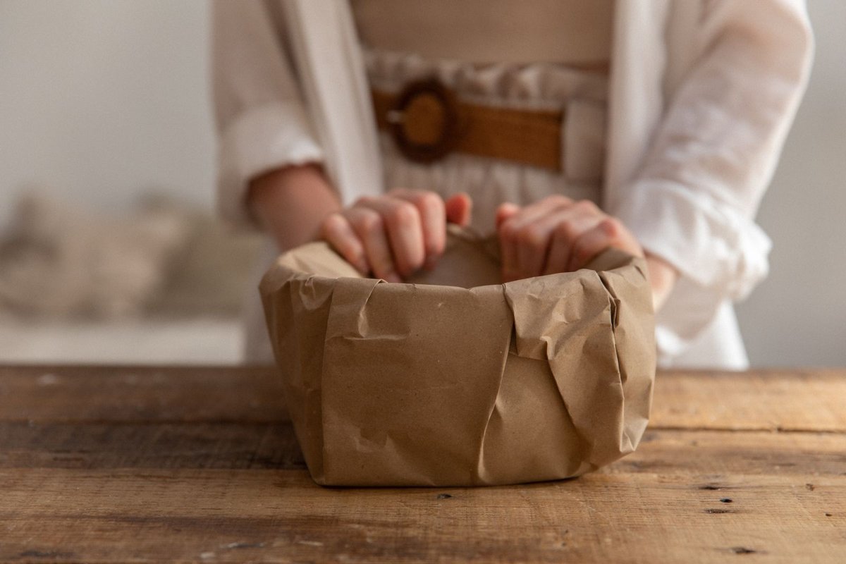 Mains refermant un paquet enveloppé de papier kraft sur l'établi en bois d'un atelier