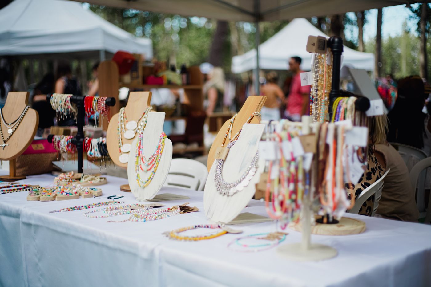 Stand de bijoux faits main sur des présentoirs en bois, marché de créateurs
